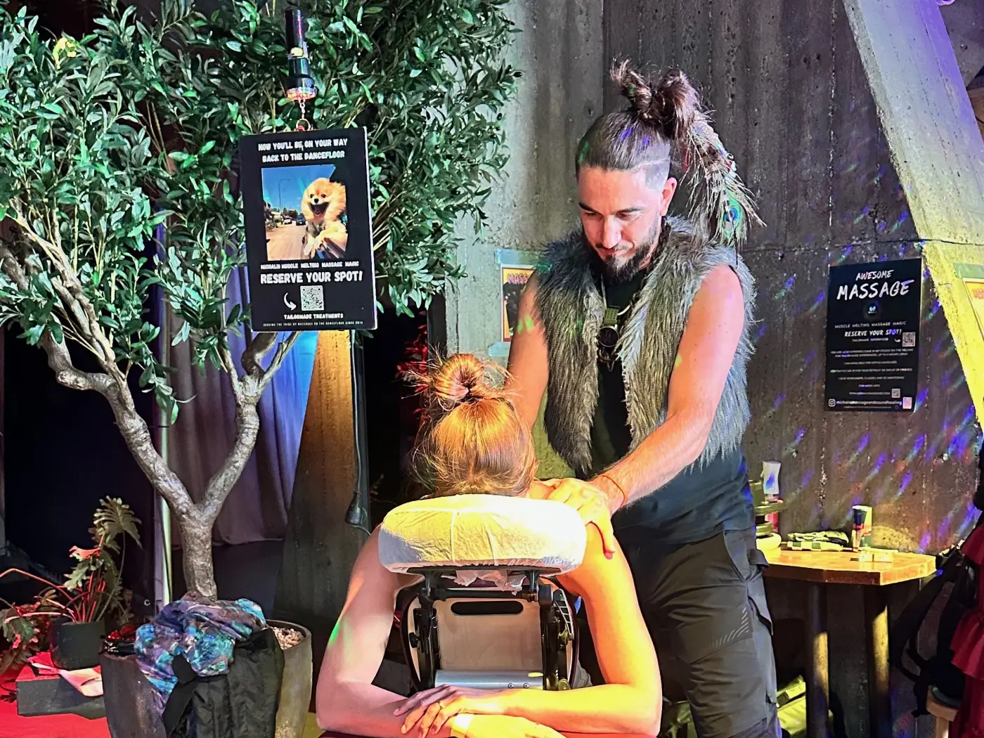 Stoelmassage op een festival onder discolicht, schouderbehandeling